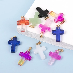 Pendentifs croix en verre coloré avec attaches dorées sur décor de pierre épuré