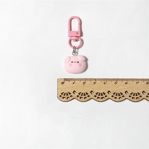 Close-up of pink pig resin keychain with metal clasp showing size next to a wooden ruler