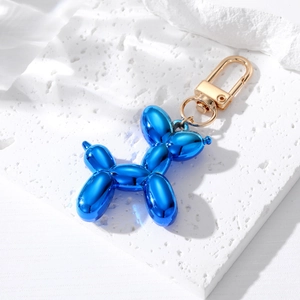 Polished royal blue electroplated balloon dog keychain with golden lobster clasp on white stone