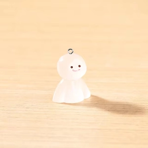 Gros plan d'un pendentif fantôme en résine blanche avec anneau sur fond de bois clair