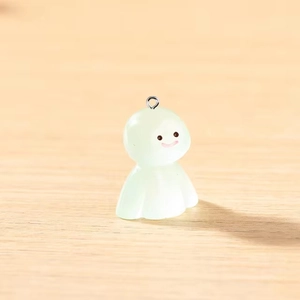 Pendentif fantôme en résine verte lumineuse avec un sourire mignon sur bois clair