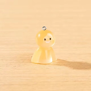 Détail d'un pendentif fantôme en résine jaune avec anneau argenté sur fond de bois clair