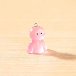 Détail d'une breloque fantôme rose translucide avec visage souriant et anneau métallique
