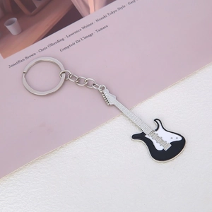 Macro view of a mini electric guitar keychain in black and white finish on a magazine