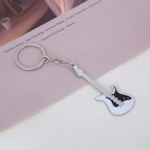 Close-up of a white electric guitar keychain with black pickguard and metal chain