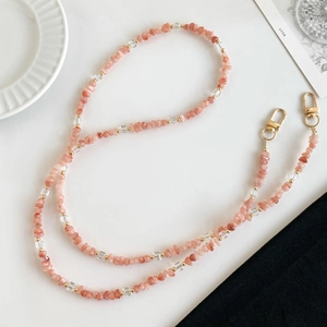Lanière de téléphone avec quartz rose et perles d'eau douce sur fond blanc minimaliste