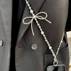 Detail of beaded crossbody phone chain with pearls and silver bow on black case