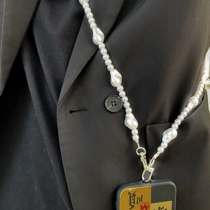 Baroque irregular pearl phone chain strap with silver metal clasp on black jacket background