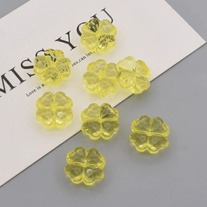 Macro view of translucent yellow acrylic clover beads with faceted surface for DIY jewelry