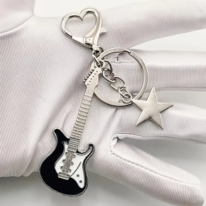 Detail of an electric guitar keychain with a heart buckle and star pendant accessory