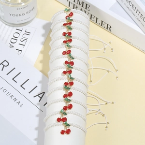 Set di 12 braccialetti di perle con ciondolo ciliegia rossa su supporto bianco