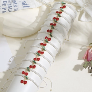 Elegante set di braccialetti di perle con ciondoli a ciliegia su supporto bianco