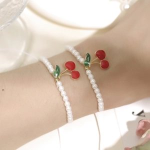 Dettaglio ravvicinato del bracciale con perle e ciliegie con cristalli sul polso