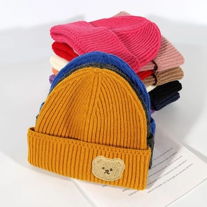 Macro shot showing vertical knit texture and brown bear patch on colorful winter beanies
