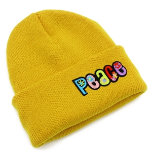 Detailed close-up of yellow knit beanie featuring colorful PEACE letter embroidery