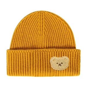 Detail of mustard yellow ribbed knit beanie featuring a cute plush bear patch