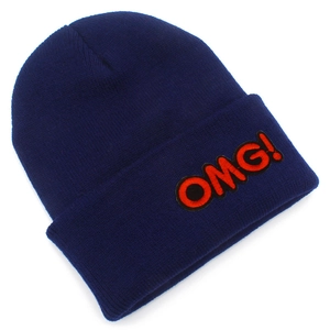 Detailed view of the 'OMG!' embroidered letter patch on a dark blue knitted beanie
