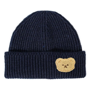 Detailed close-up of navy blue ribbed knit beanie featuring a cute plush bear patch