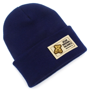 Détail d'un bonnet en maille côtelée bleu marine avec écusson décoratif cousu original