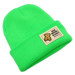 Détail du bonnet en maille vert néon avec texture côtelée et écusson d'ours