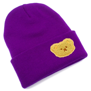 Dettaglio del berretto in maglia viola a coste con toppa decorativa a forma di orsetto