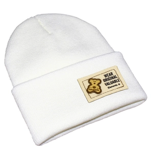 Détail du bonnet en maille blanche côtelée avec écusson ours et slogan original brodé