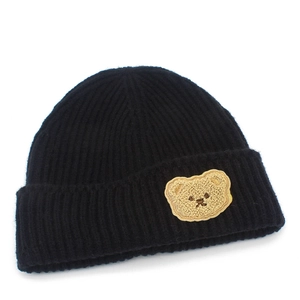 Detail view of the black ribbed knit beanie featuring a cute beige bear plush patch
