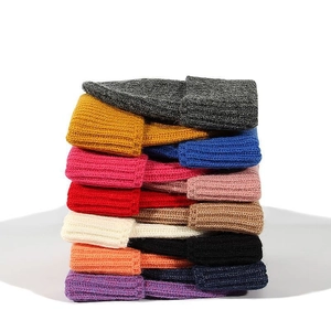 Vertical stack of rib-knit beanies showing twelve vibrant colors and thick warm texture