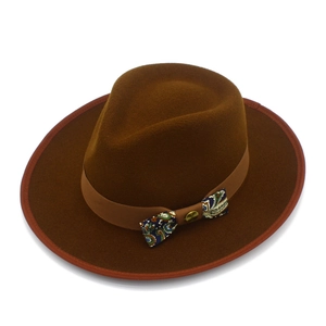 Detailed shot of dark brown wool fedora featuring a paisley bow and golden button accent