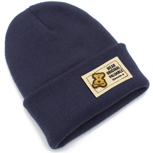 Détail du bonnet en maille bleu marine avec texture côtelée et étiquette ours décorative
