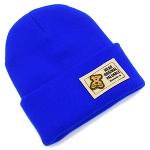 Détail d'un bonnet en maille bleu vif avec écusson d'ours et broderie décorative