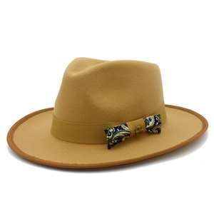 Detail of camel wool fedora hat featuring paisley patterned bow and bronze buckle