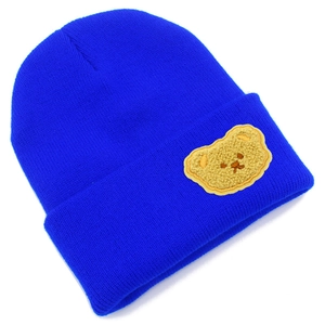 Dettaglio del berretto in maglia blu acceso con applicazione di un orsetto giallo