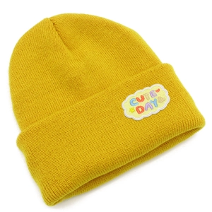 Détail d'un bonnet en tricot jaune avec écusson en forme de nuage et texte coloré brodé