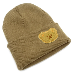 Dettaglio berretto in maglia kaki con toppa orsetto di peluche giallo e texture a coste fini
