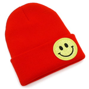 Détail d'un bonnet en maille rouge avec un écusson smiley jaune scintillant brodé