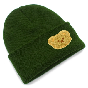 Dettaglio di un berretto in maglia verde scuro con una toppa a forma di orsetto beige