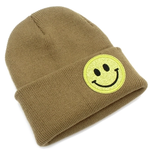 Détail du bonnet en maille kaki avec un écusson brodé visage souriant jaune à paillettes