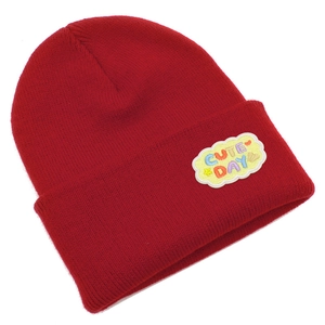 Détail d'un bonnet en tricot rouge avec un écusson brodé Cute Day en forme de nuage