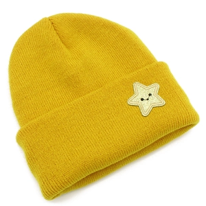 Close-up of yellow knitted beanie featuring a star embroidery with a black smiley face