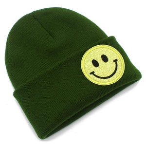 Détail du bonnet en tricot vert foncé avec un patch smiley jaune à paillettes