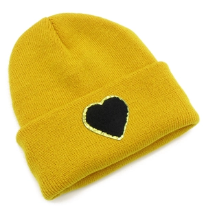 Close-up of yellow knit beanie featuring a black heart patch with gold glitter edges