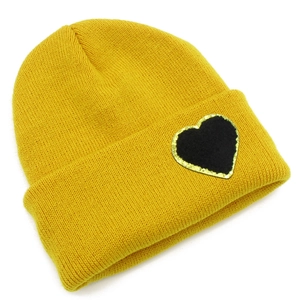 Close-up of bright yellow knit beanie featuring a black heart patch with gold sequins