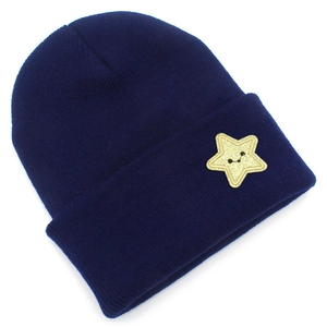 Close-up of navy knit beanie with yellow glitter star patch and smile embroidery
