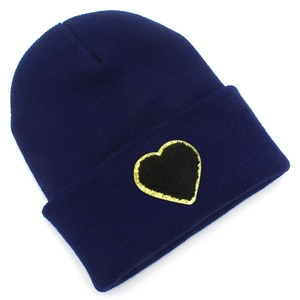 Close-up of heart patch with gold sequin trim on navy blue knitted beanie hat