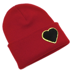 Detail of red knit beanie featuring a black heart patch with golden glitter embroidery