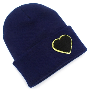 Close-up of navy blue knit beanie featuring a black heart patch with gold sequin edges