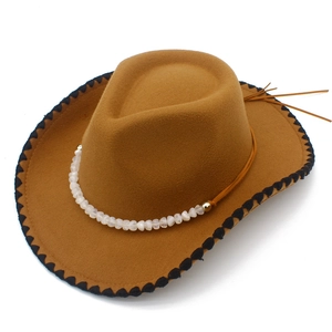 Detail of a brown cowboy hat with decorative bead chain and black wavy edge stitching