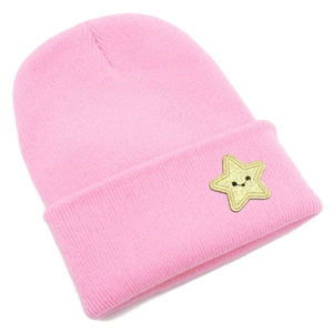 Detailed knit texture of pink beanie with a yellow smiley star patch on the folded brim