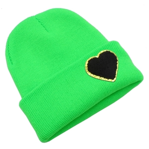 Detail of neon green knit beanie featuring a black heart patch with gold glitter borders
